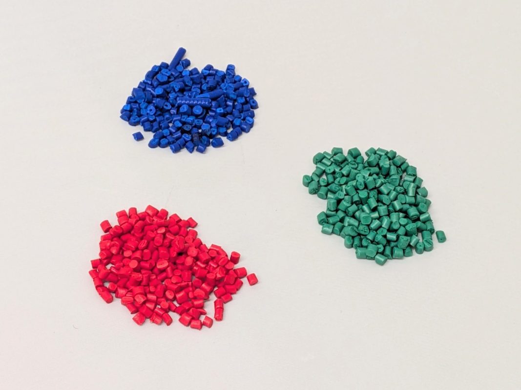 Three piles of pigment granules. One pile is red, one is blue and and the other one is green.